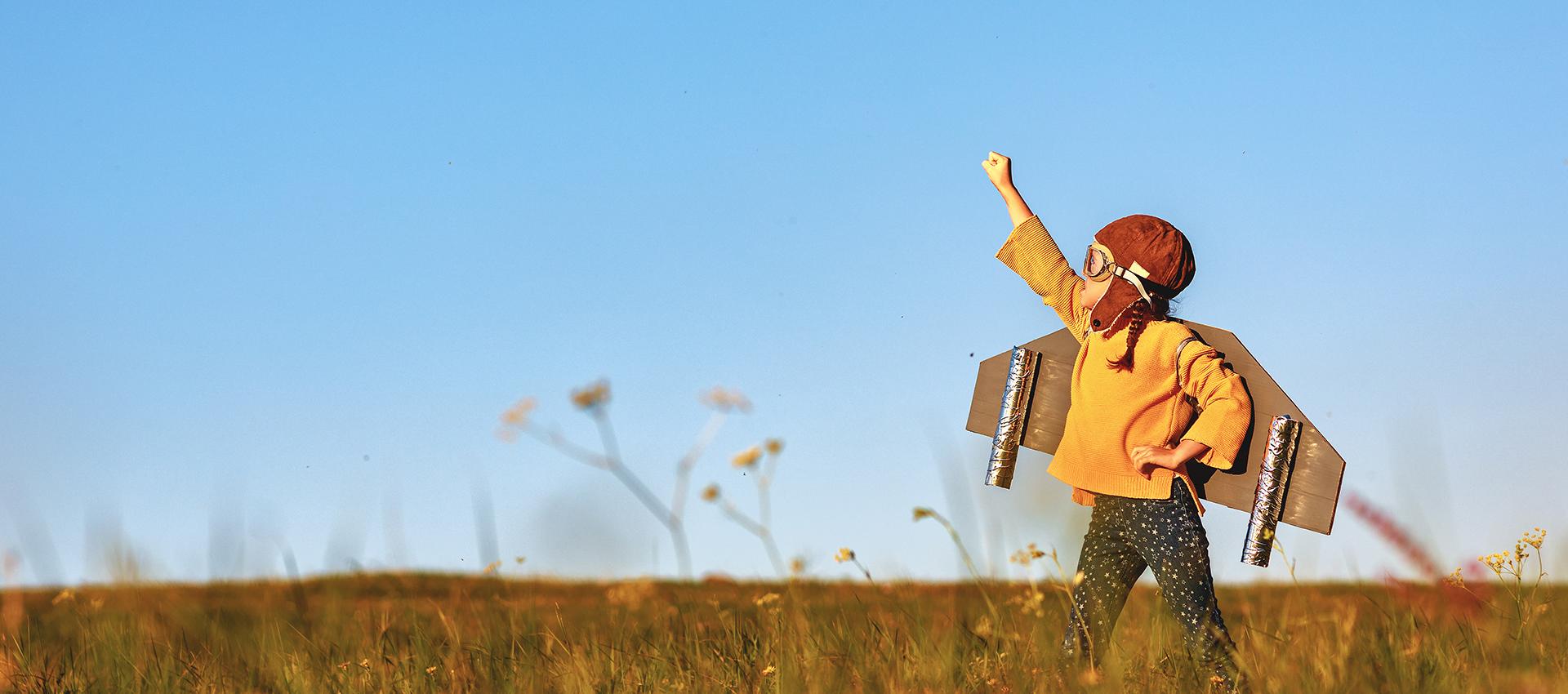 Kind verkleidet als Pilot mit gebastelten Flügeln auf dem Rücken